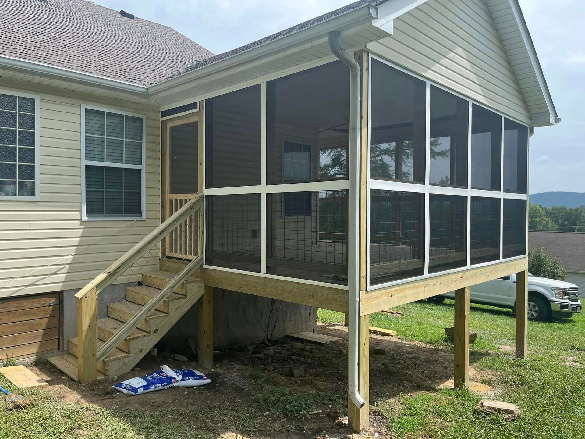 A screened in porch is being built on the side of a house.