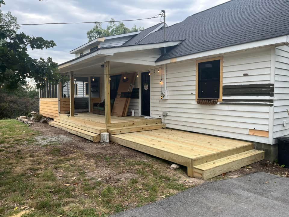 A white house with a wooden deck in front of it.