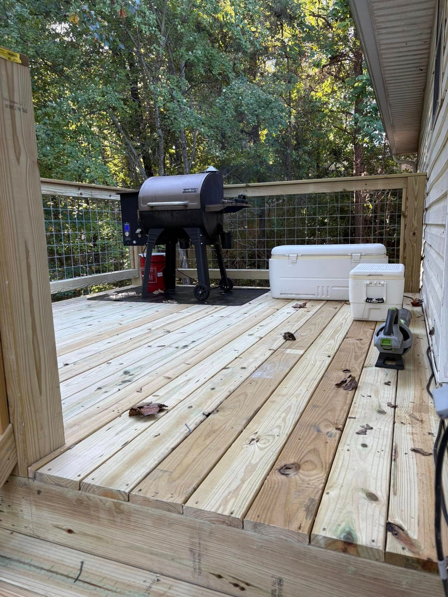A wooden deck with a grill and cooler on it.