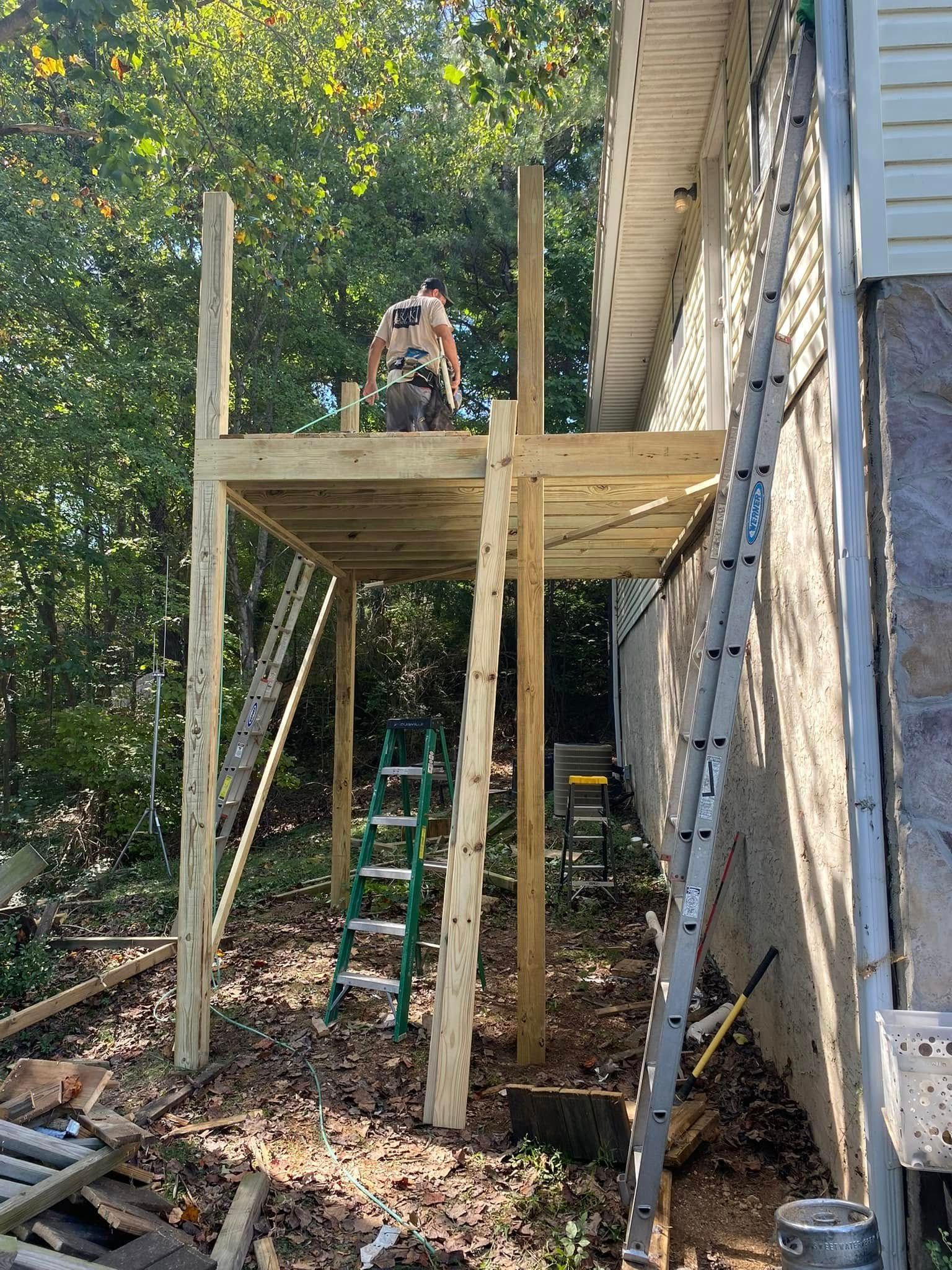 A man is standing on a wooden platform in front of a house.