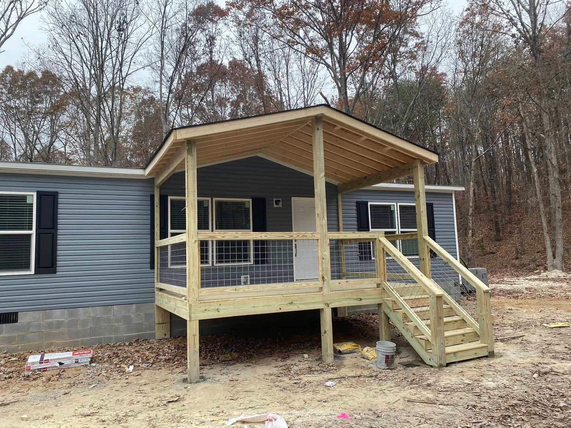 A mobile home with a wooden deck and stairs in front of it.