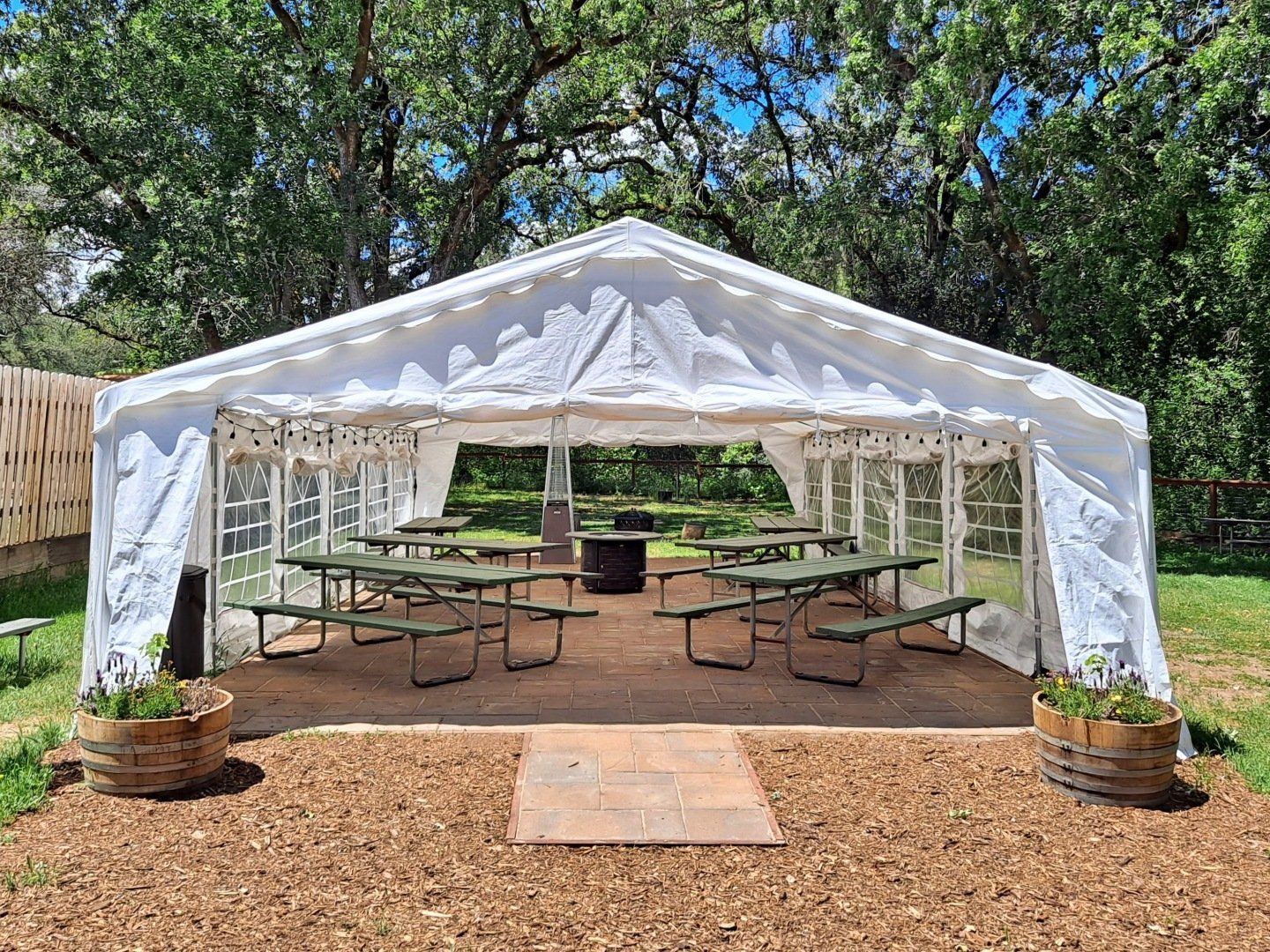 large canvas event tent on grass with large trees surrounding area