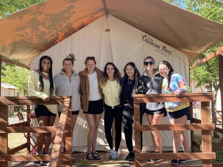 group of happy people in front of glamping tent