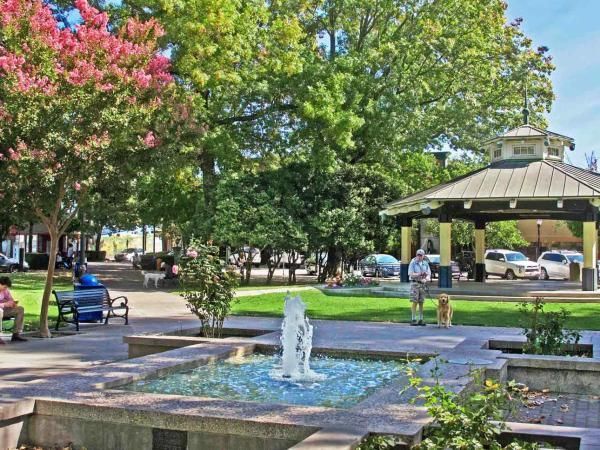 A fountain in a park with a gazebo in the background