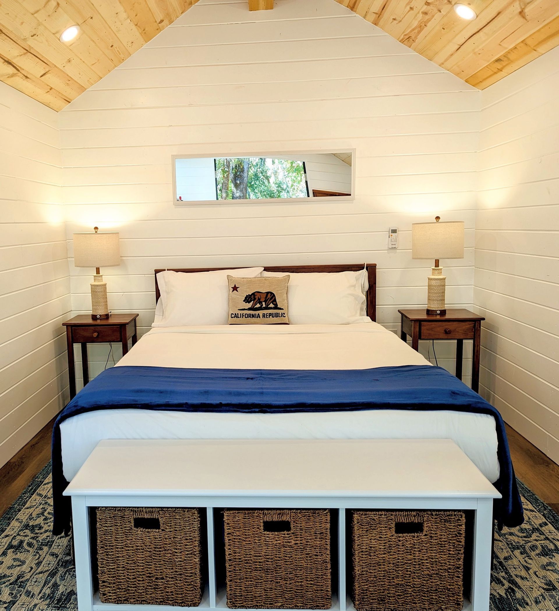 A bedroom with a bed and a bench with baskets underneath it