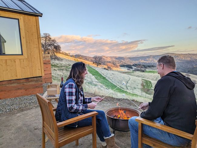 A man and a woman are sitting in chairs near a fire pit.