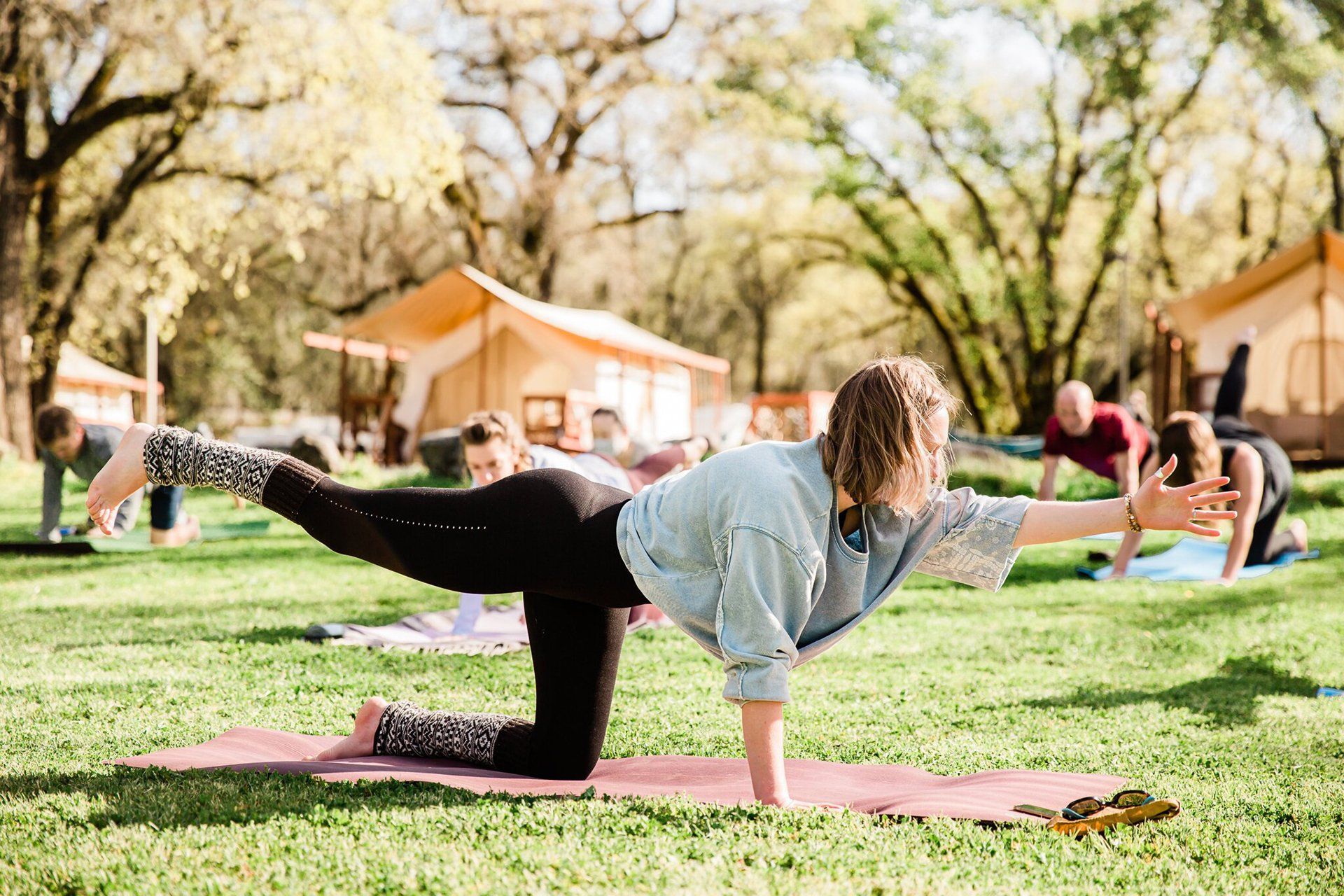 woman teaching group of people yoga outdoors