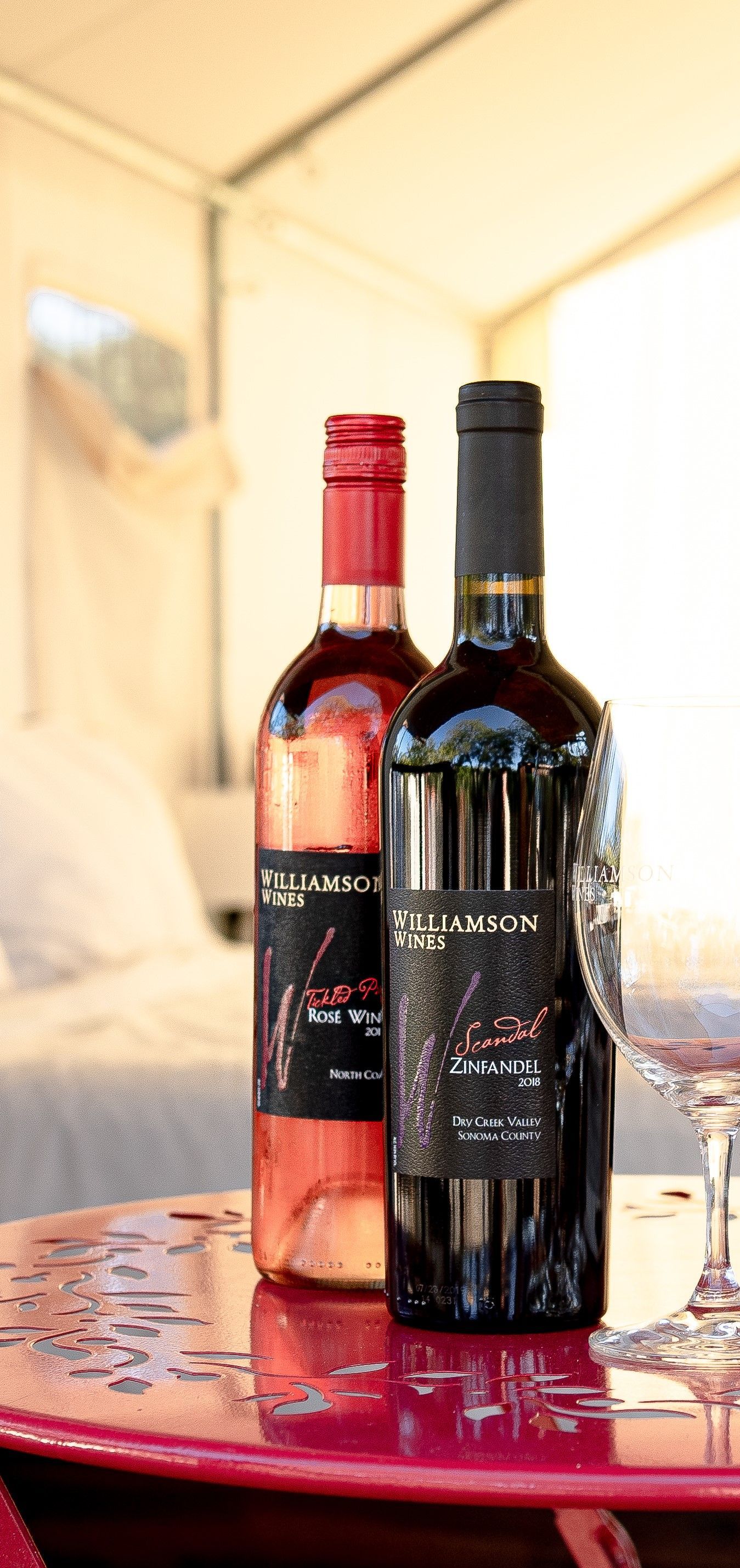 Two bottles of wine and a glass of wine are on a table.