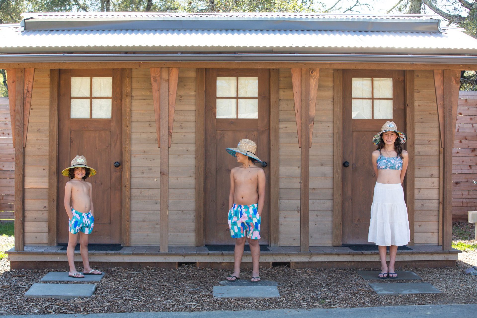 A woman and two children are standing in front of a wooden building.