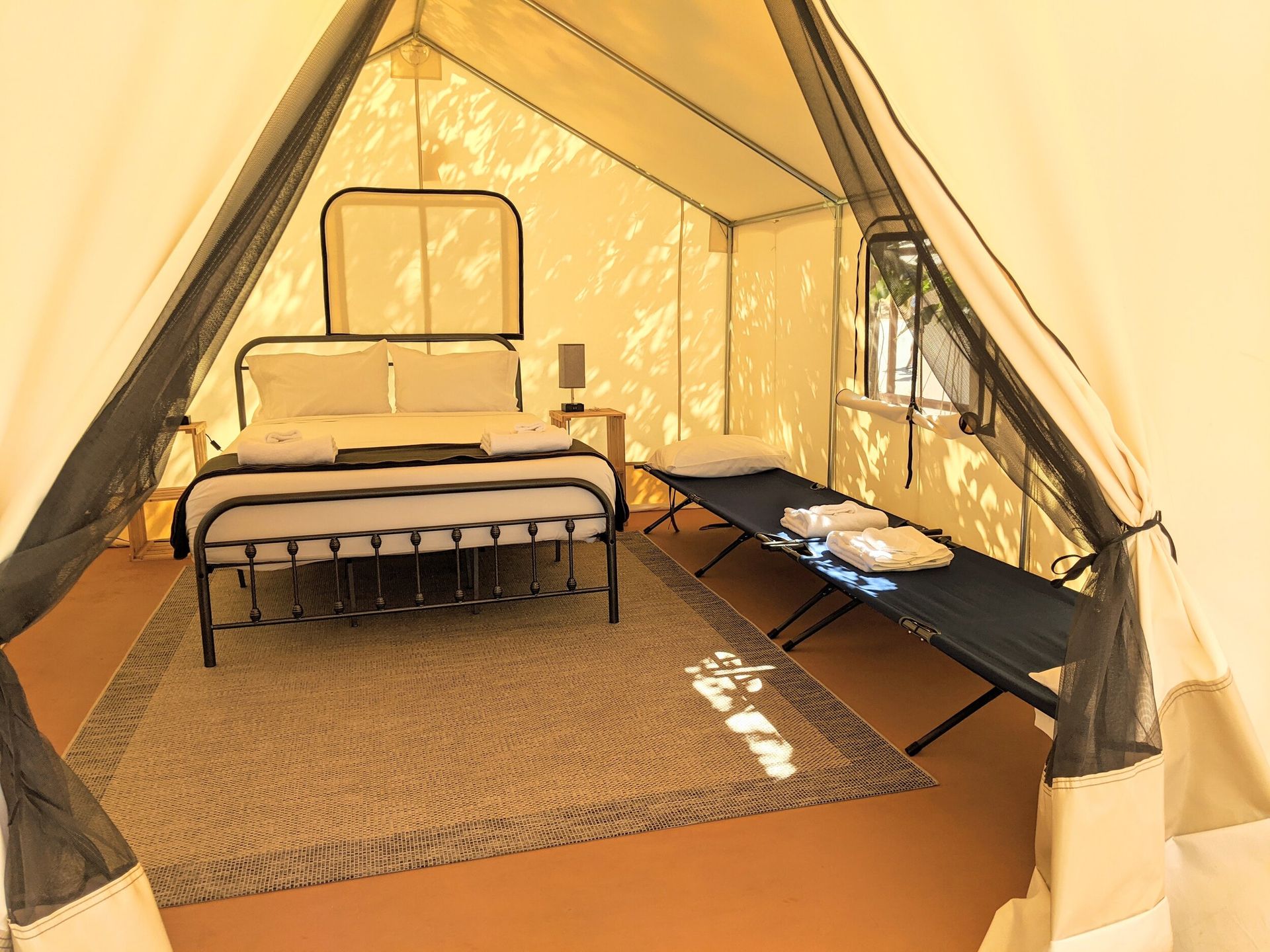 A tent with a bed and a bench inside of it.