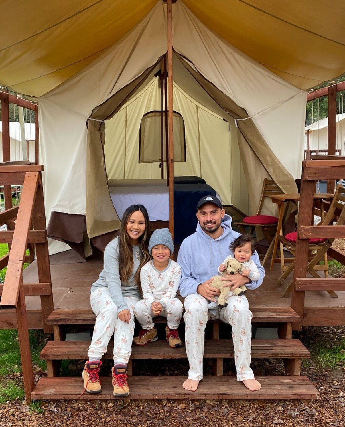 A family is sitting on the steps of a tent.