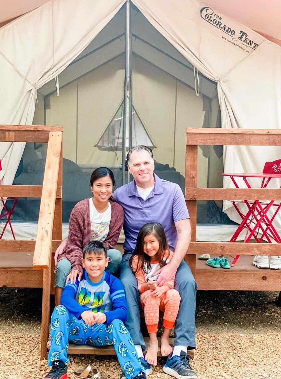 A family is posing for a picture in front of a tent.