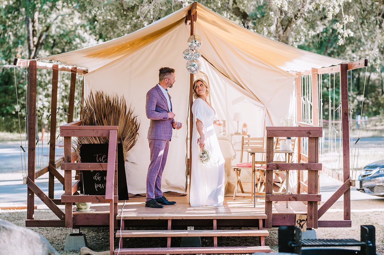 A bride and groom are standing in front of a tent.
