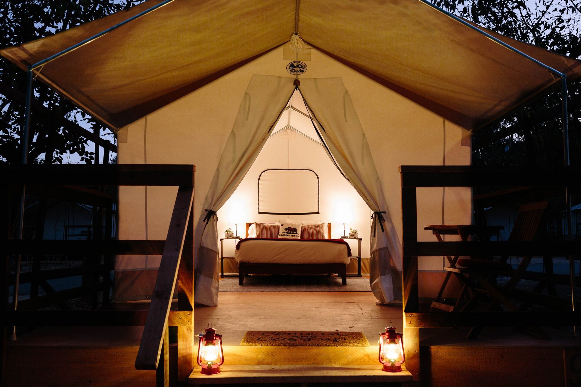 A tent with a bed and lanterns inside of it