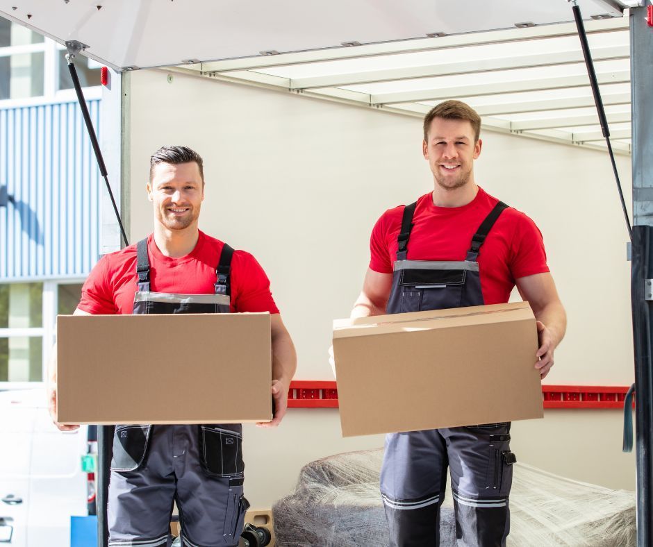 Two men are carrying boxes out of a moving truck.