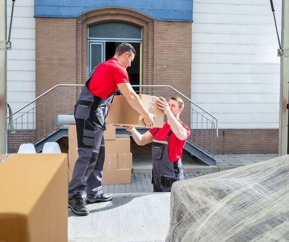 Two men are carrying boxes into a building.