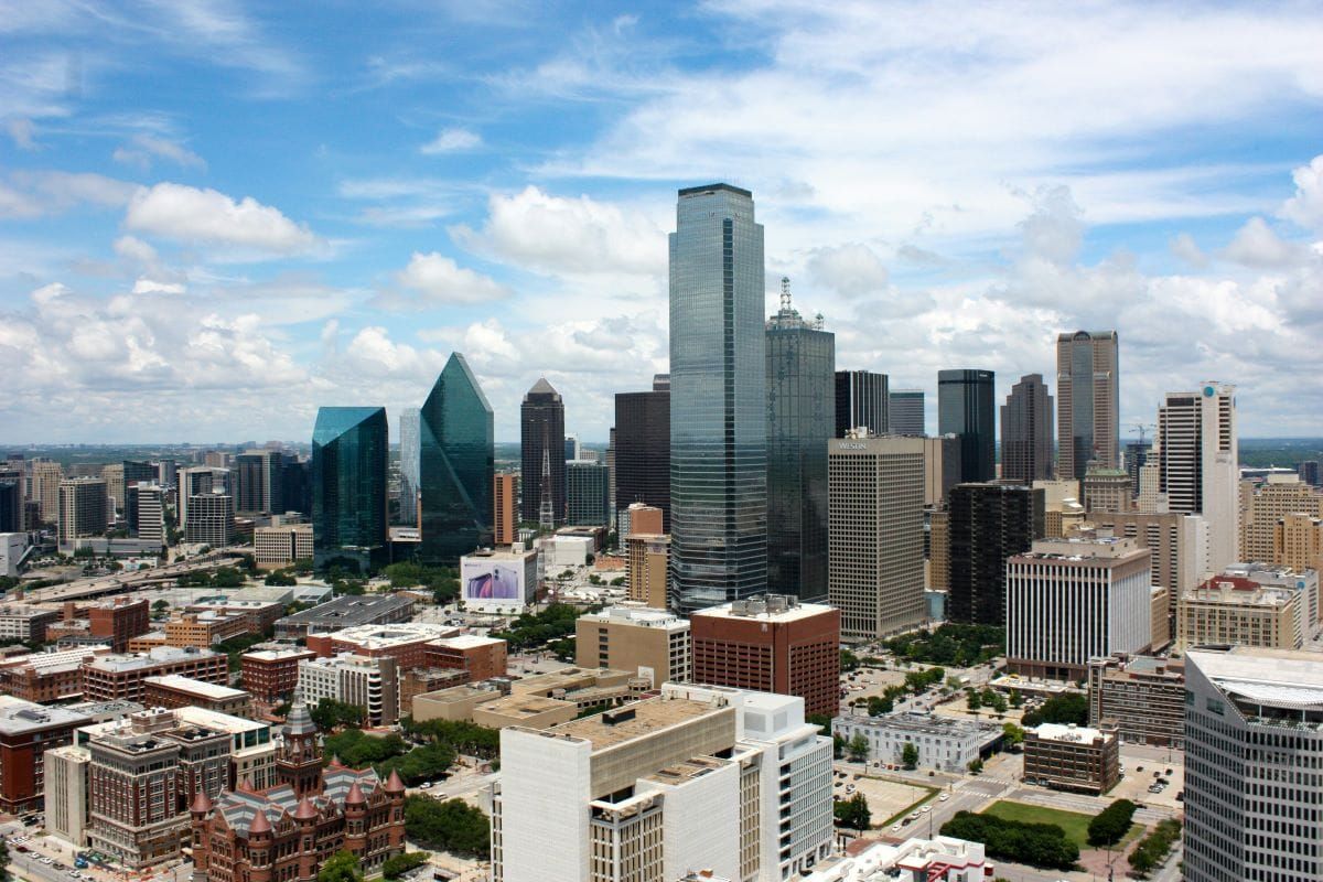 Aerial view of the Dallas, Texas skyline on a bright summer day, featuring modern glass skyscrapers
