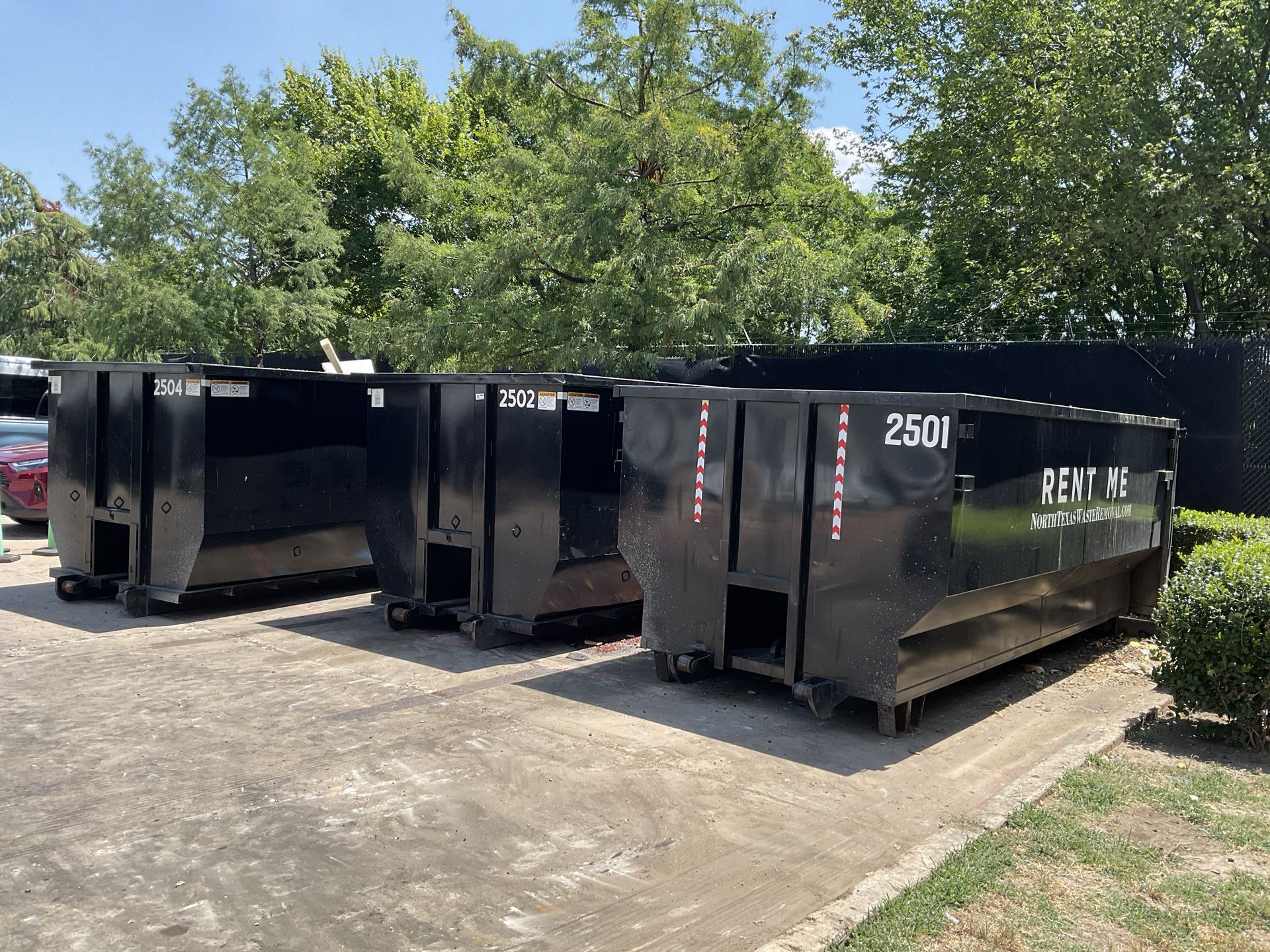 Three dumpsters are parked next to each other in a parking lot.