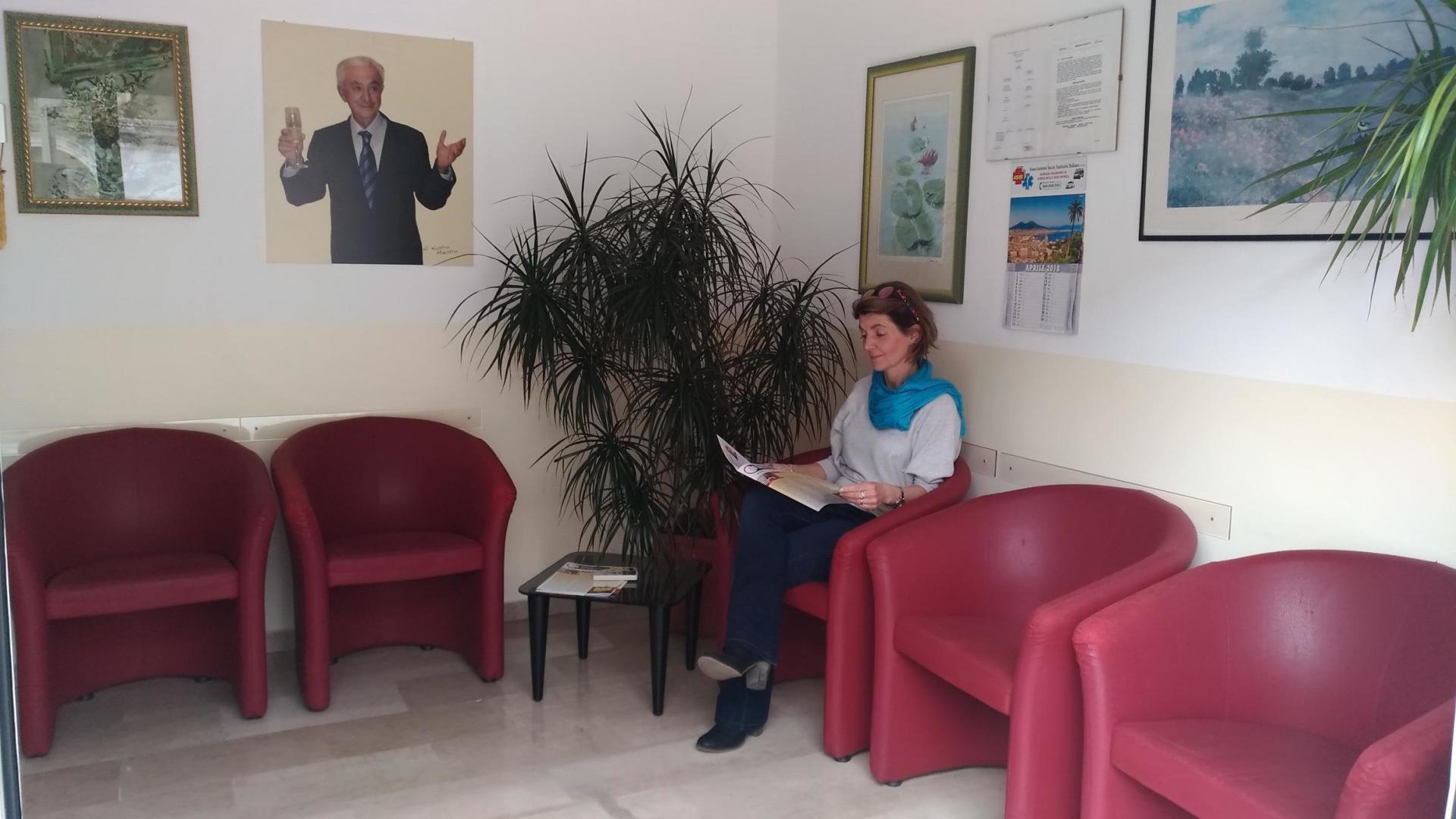 Una donna è seduta in una sala d'attesa e legge un libro