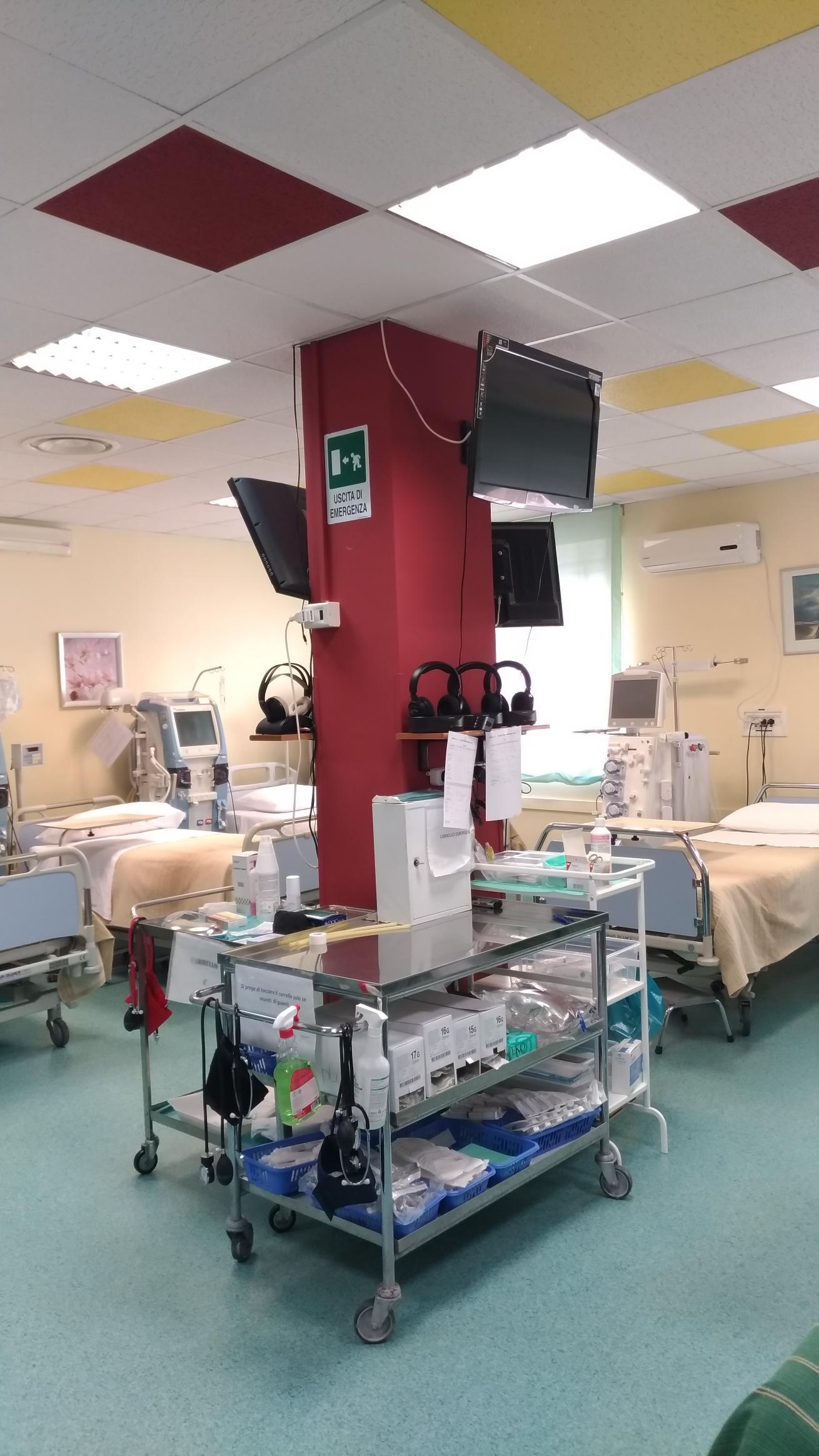 Una stanza d'ospedale con molti letti e un pilastro rosso