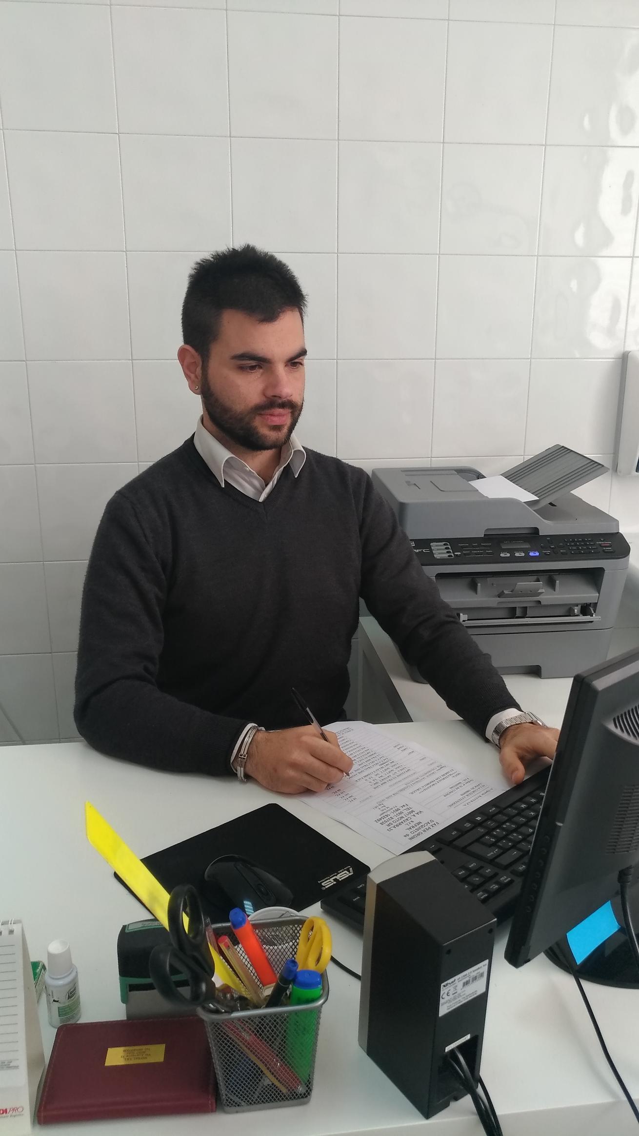 Un uomo è seduto a una scrivania davanti a un computer.