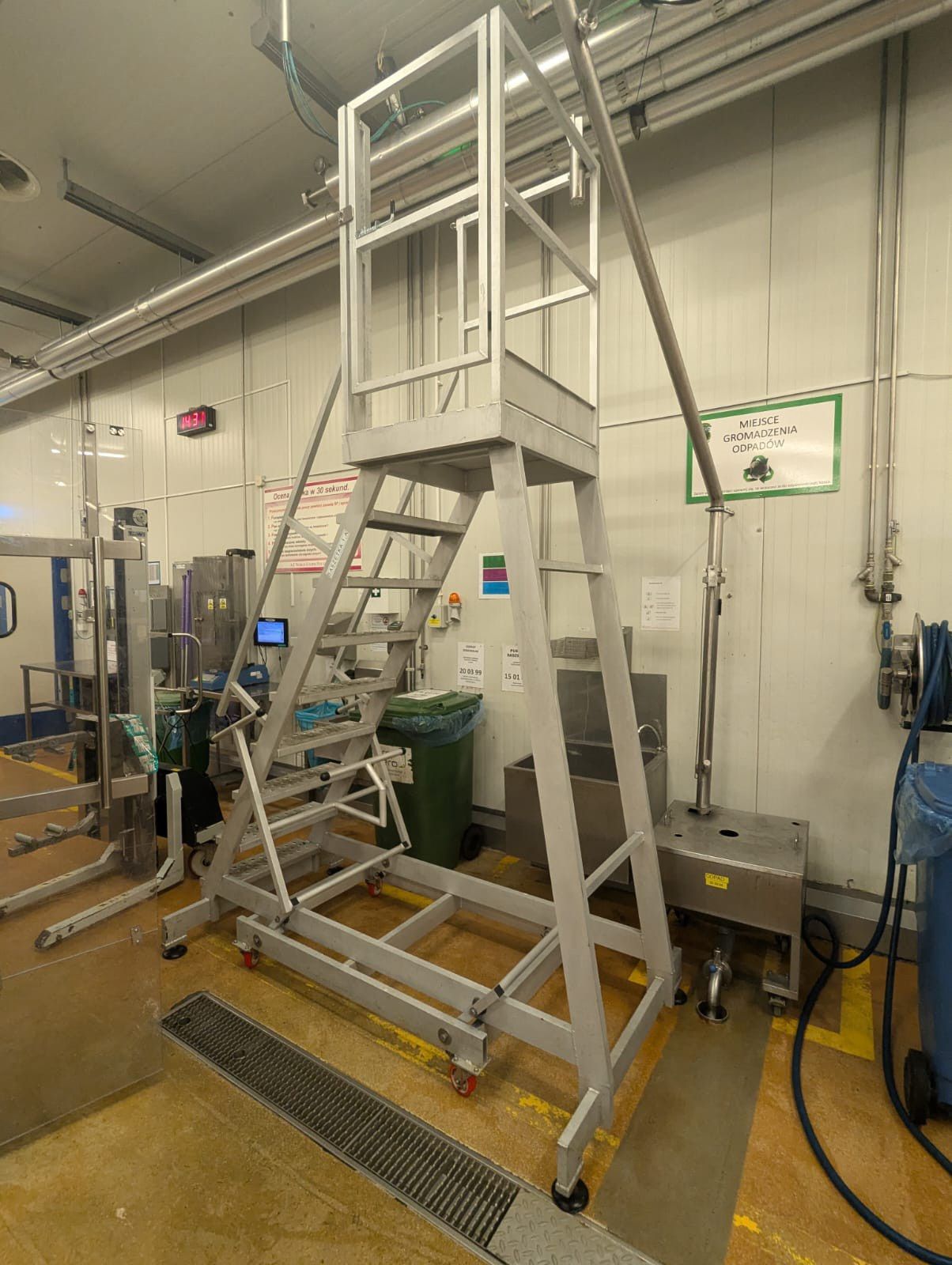 Industrial yellow steel platform with safety stairs, designed for ergonomic access over production lines in factory environment.