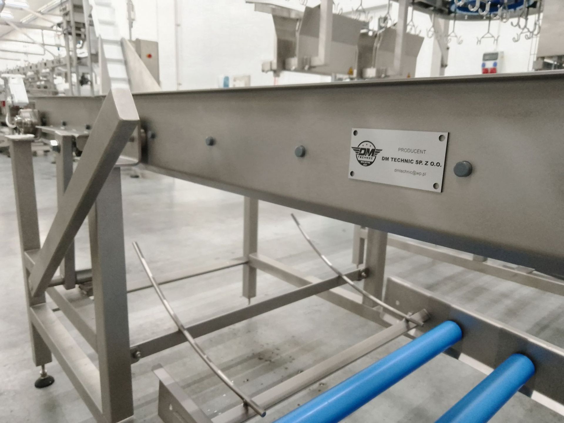 Close-up of stainless steel roller conveyor with DM Technic branding – designed for hygienic transport lines.