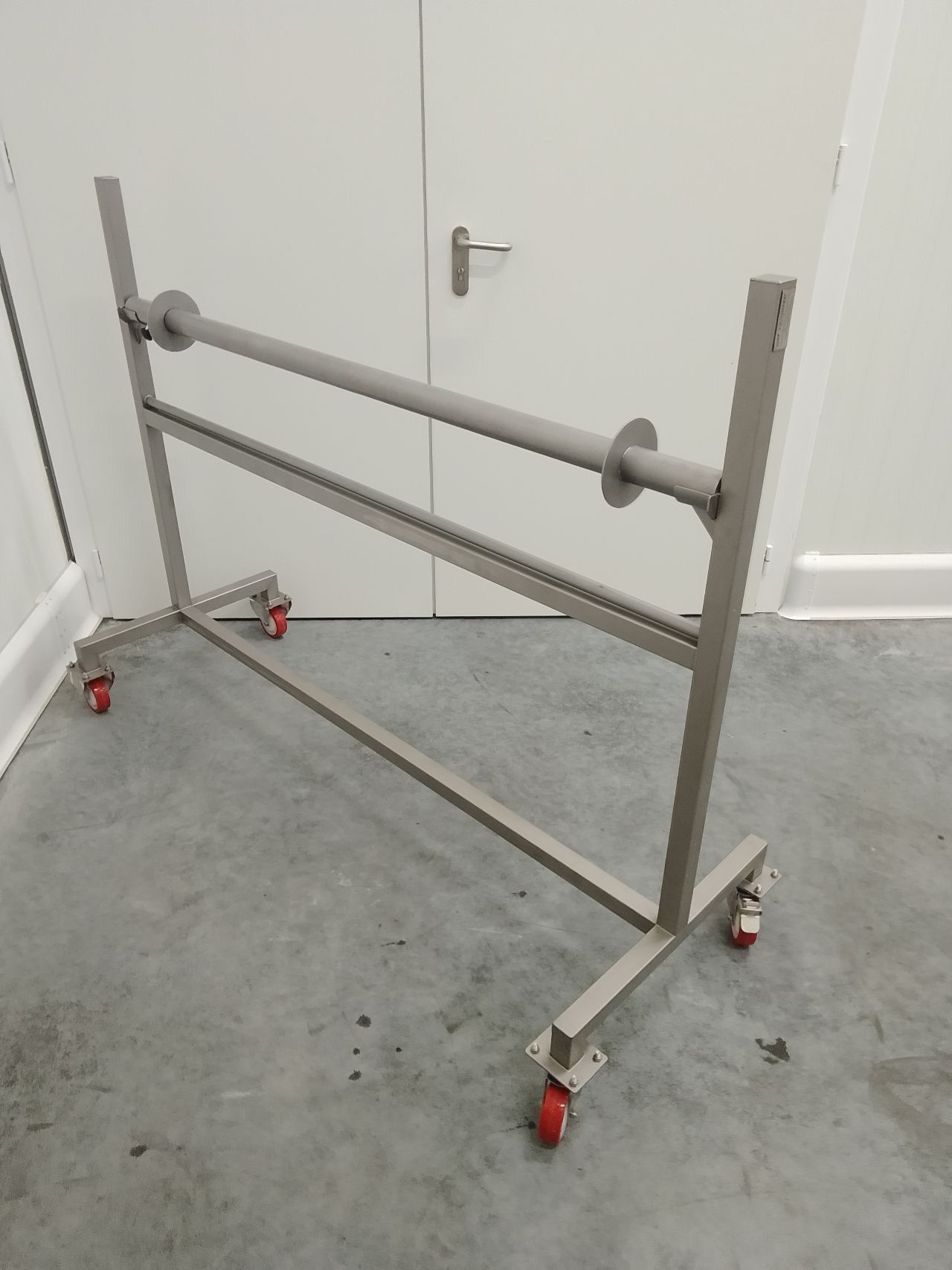 Stainless steel industrial roll holder with caster wheels for easy mobility in production environments.