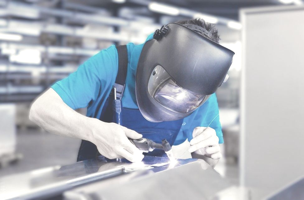 Welding DM Technic working with precision on a stainless steel component in a production hall.