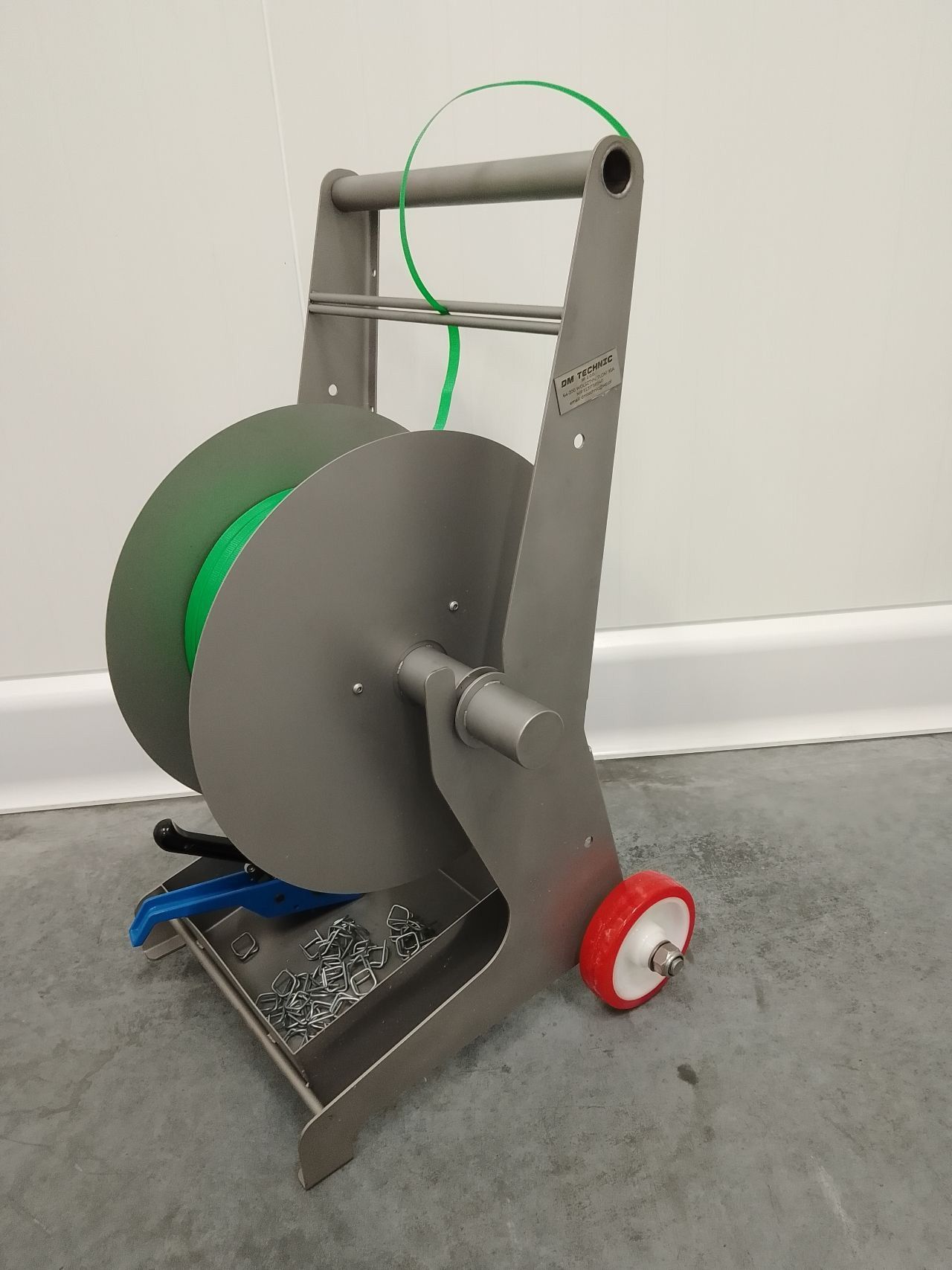 Mobile steel reel holder with green hose for industrial use, mounted on wheeled base for easy transport in manufacturing facilities.