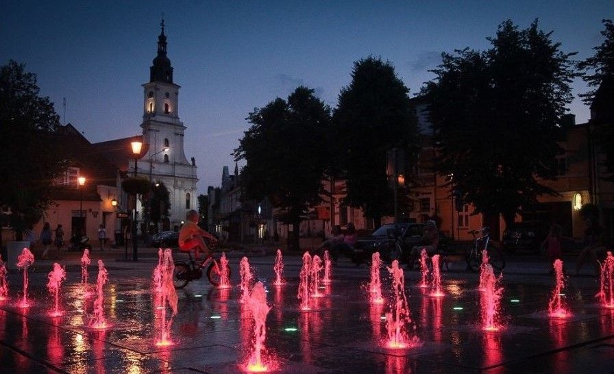 Wolsztyn town square with evening fountains and church tower — headquarters location of DM TECHNIC