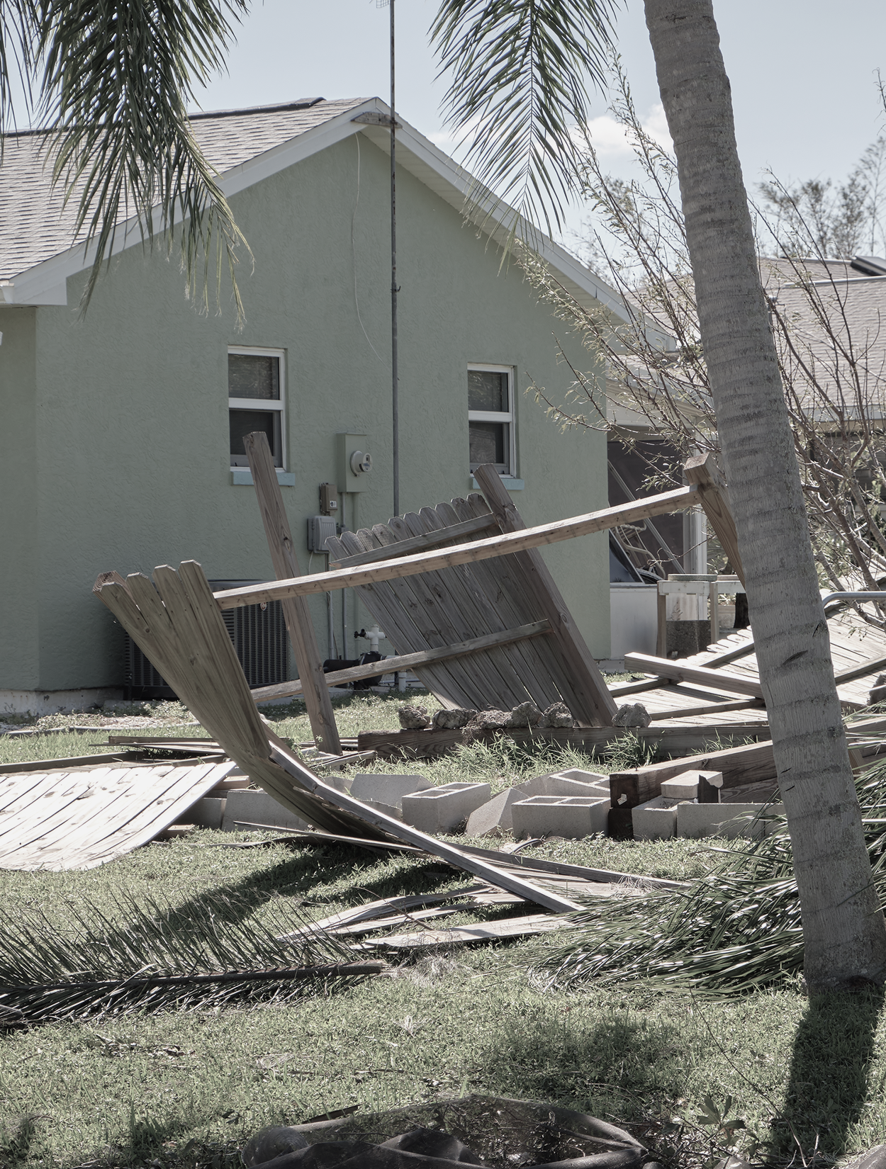 A green house with a broken fence in front of it