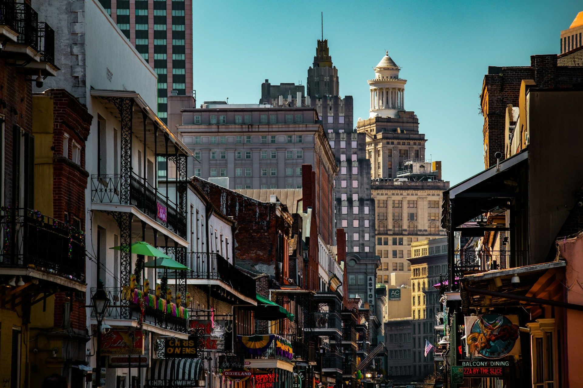 Street view in New Orleans, with historic buildings featuring balconies and skyscrapers in the background.