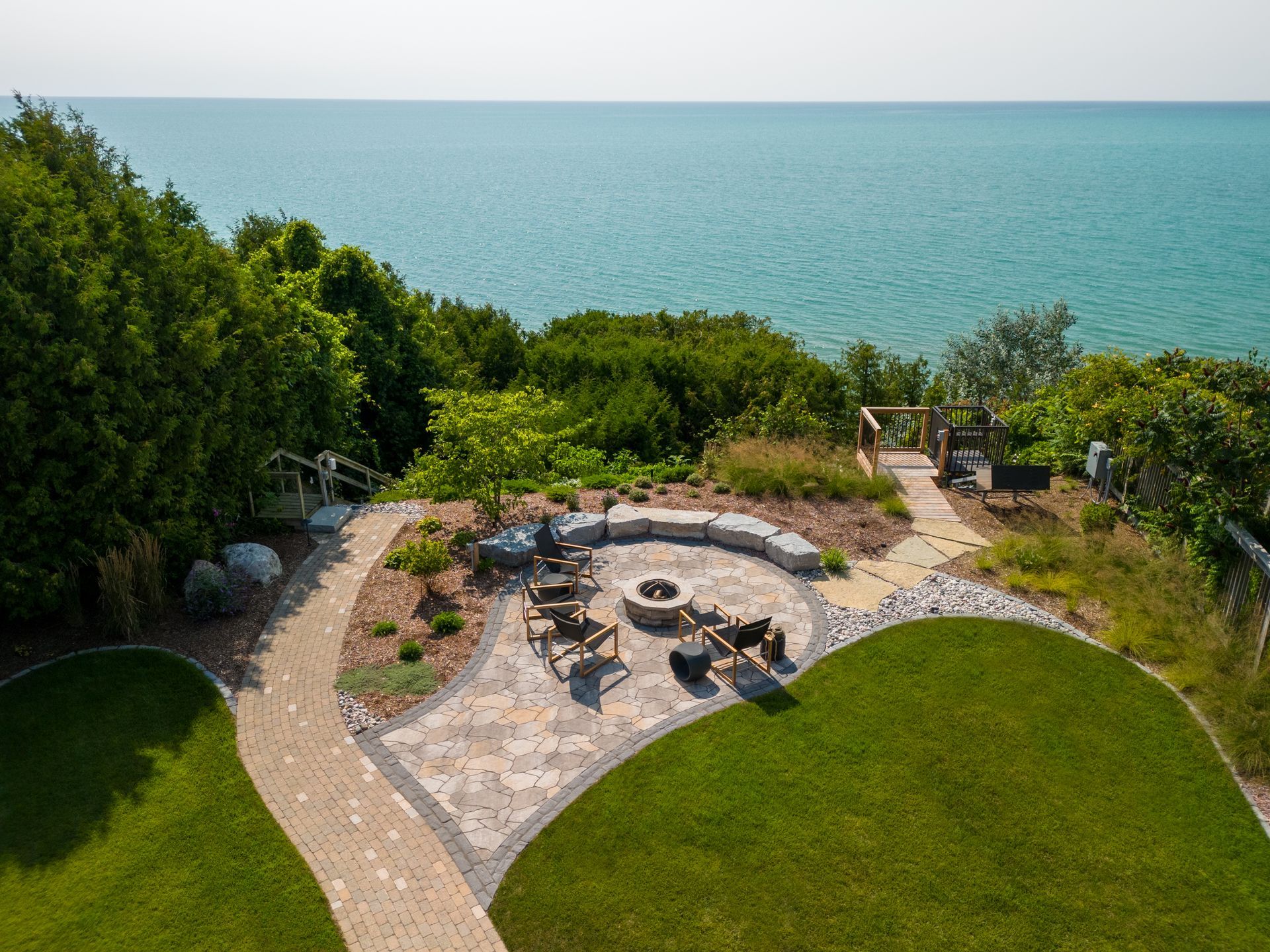 A waterside patio with a fire pit, seating, and a view of the blue ocean.
