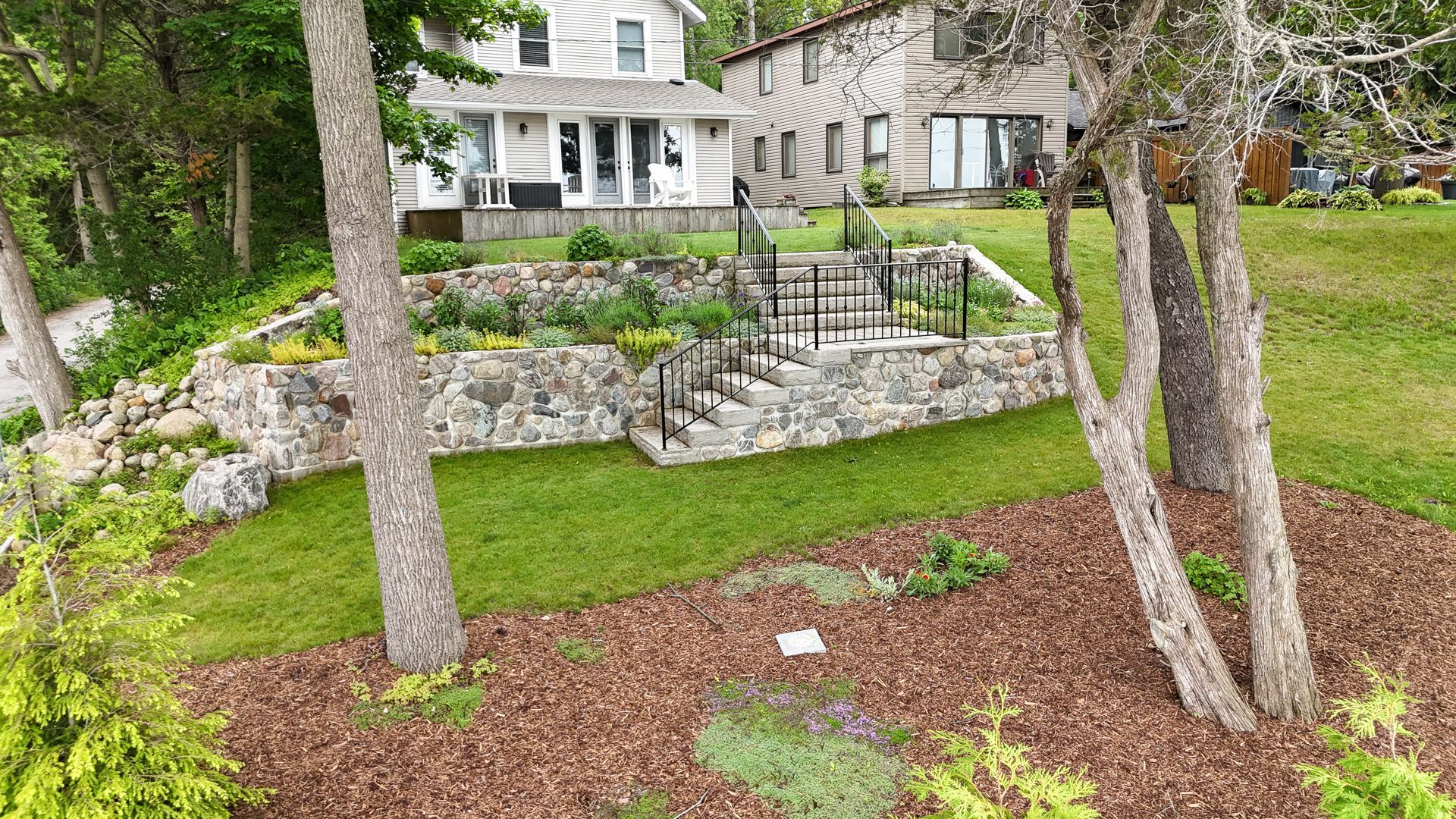 House with stone retaining walls, steps, and landscaping.