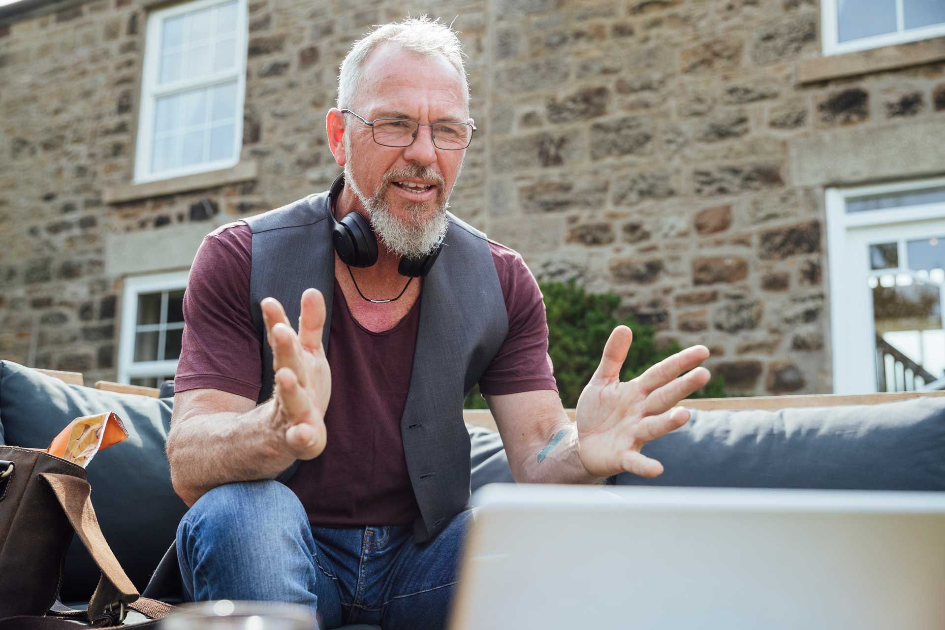 A man is sitting on a couch using a laptop computer.