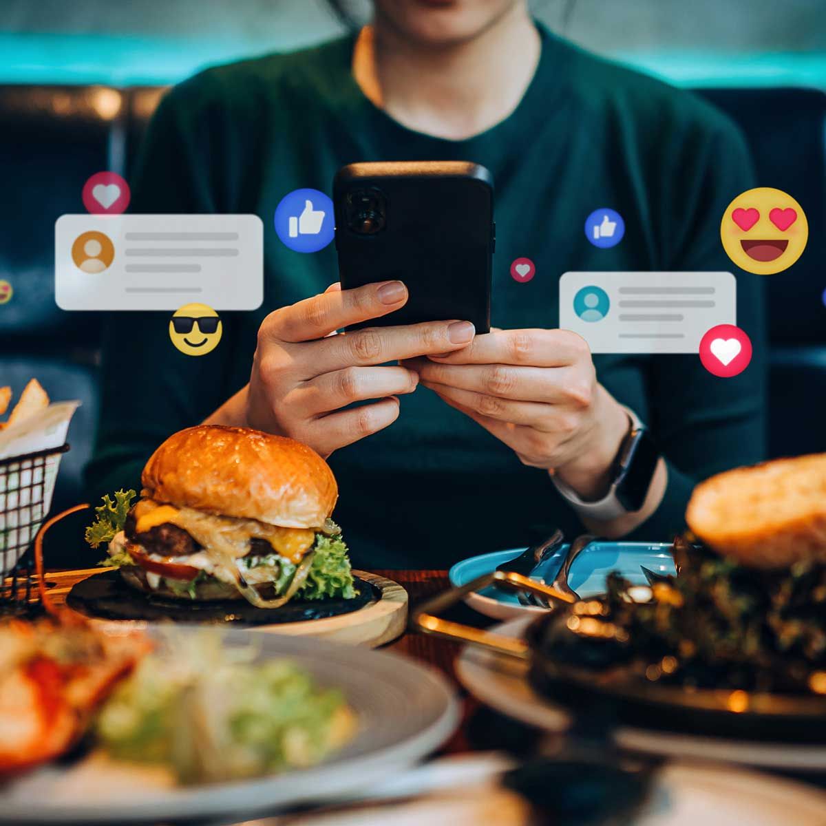 A person is sitting at a table with food and looking at their phone.