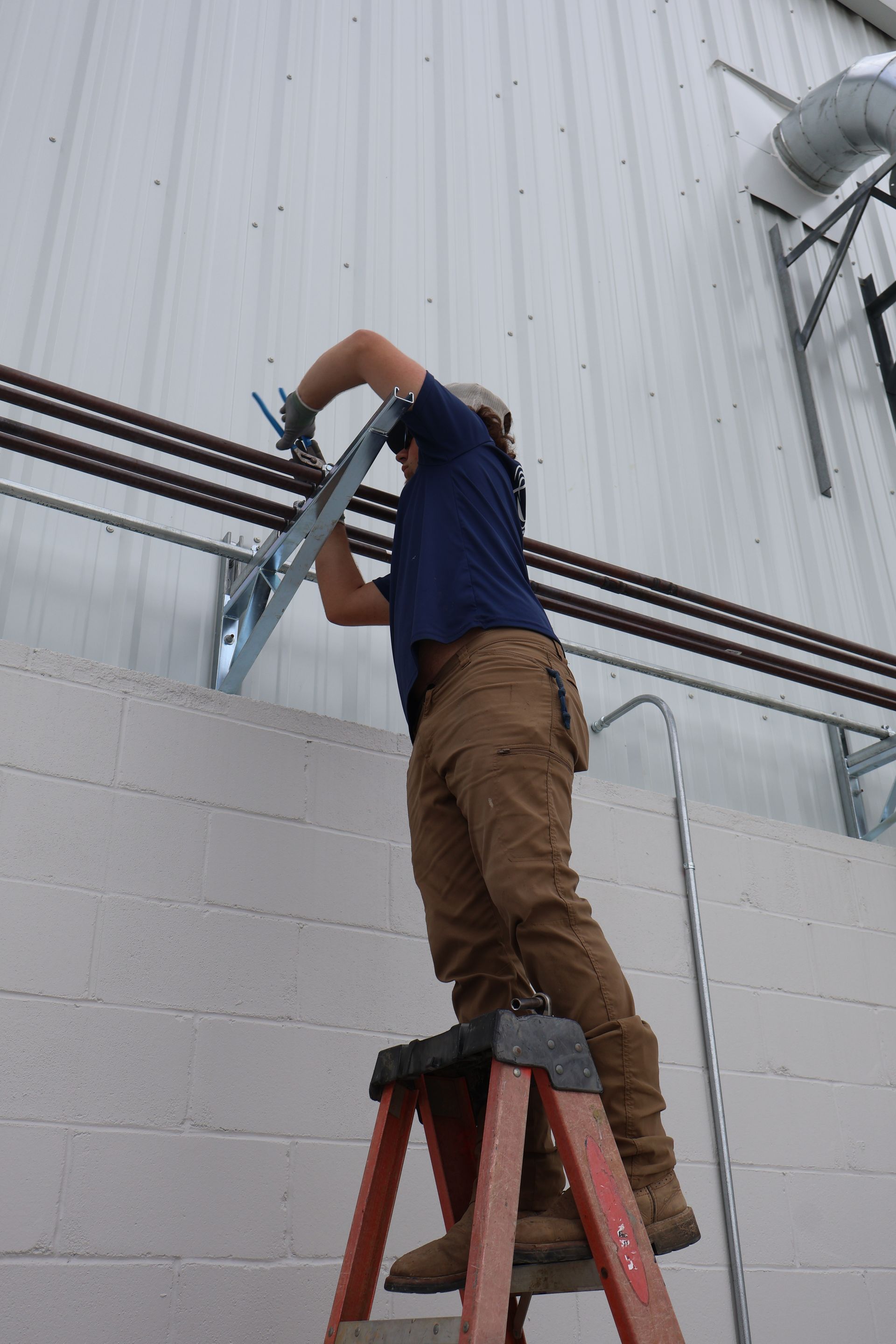 Hands using wrench to tighten plumbing under a sink.