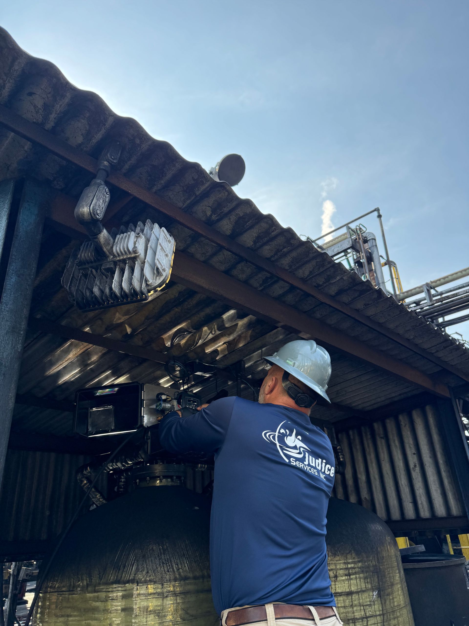 Water filtration system with two black tanks and white PVC piping in a wooden utility room.