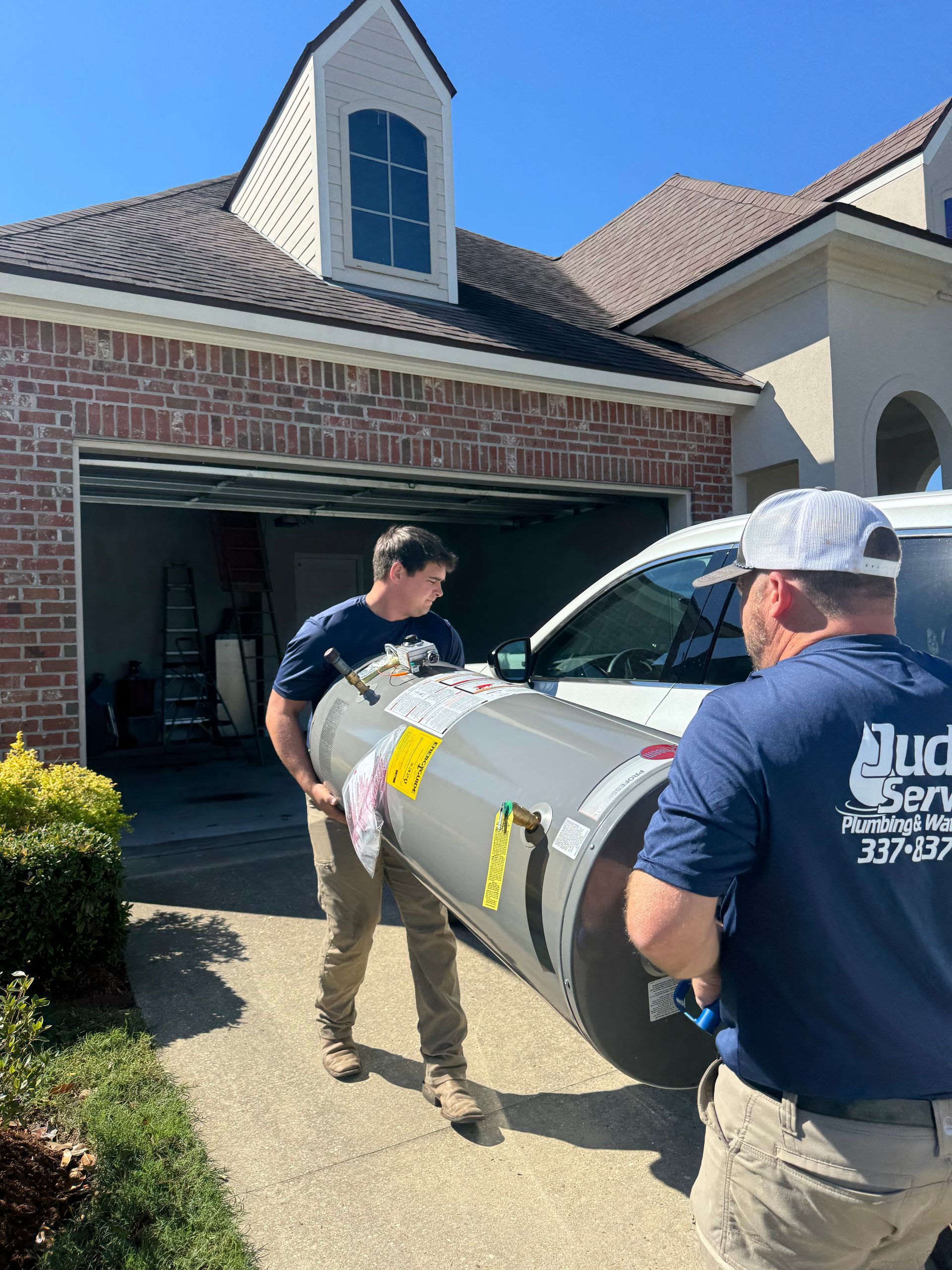 Plumber wearing a cap and overalls using pliers on a water heater.