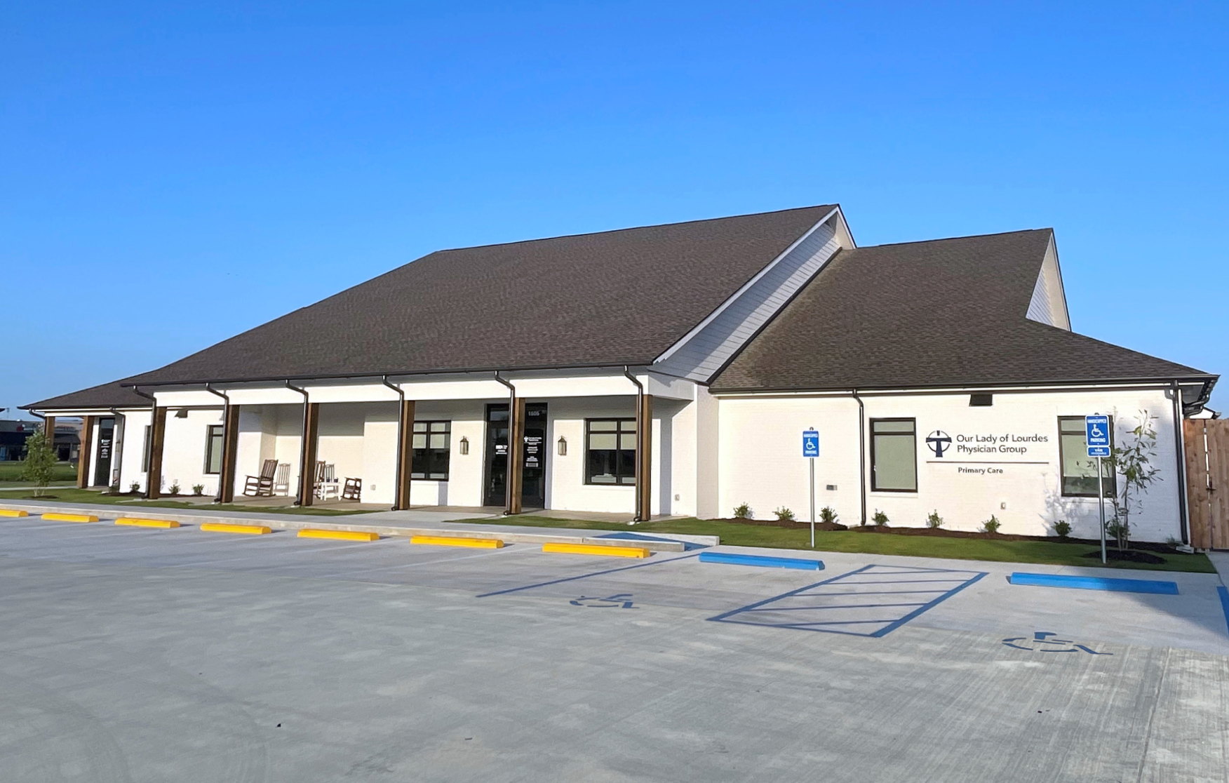 Construction site with a yellow telescopic forklift reaching towards the wooden frame of a two-story building.