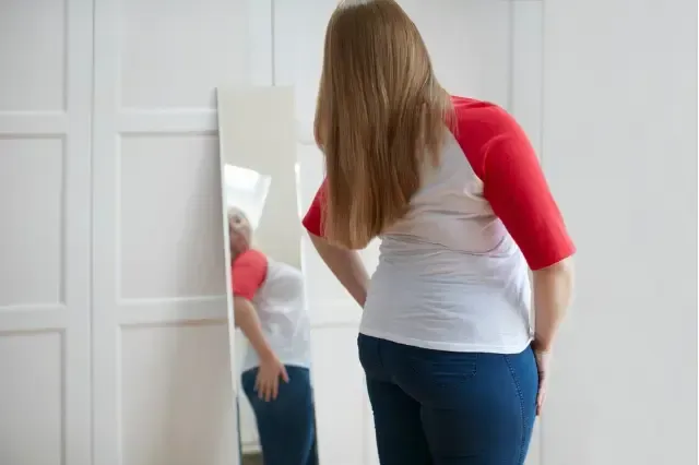 A woman is looking at herself in a mirror.