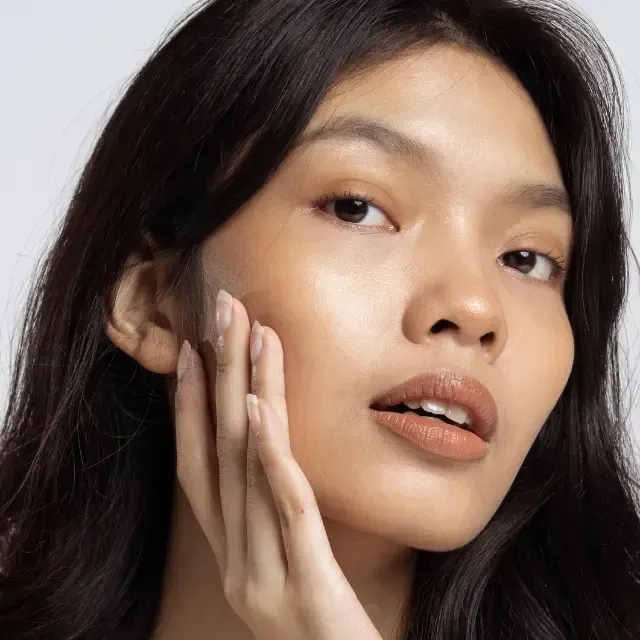 A close-up of a woman's face with her hand on her face.