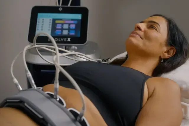 A woman is laying on a bed with a device on her stomach.