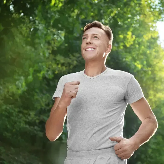 A man in a grey shirt is running in a park