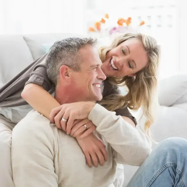 A woman is sitting on a man 's back and smiling