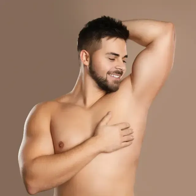A shirtless man with a beard is holding his arm over his chest.