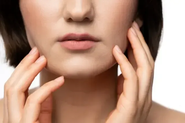 A close up of a woman 's face with her hands on it.