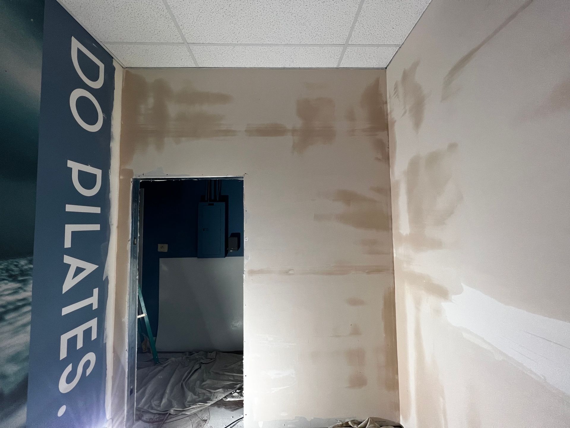 A doorway in a room under construction, with a dark blue wall on the left displaying the white text