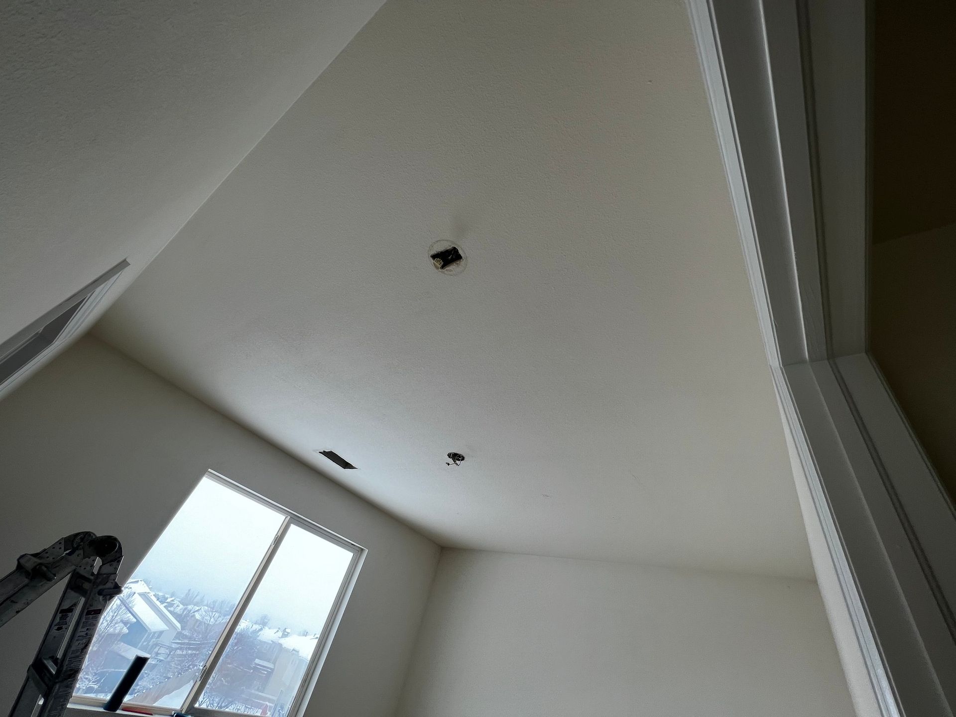 A view looking up at a white ceiling in a room under construction, featuring three open electrical boxes for fixtures.